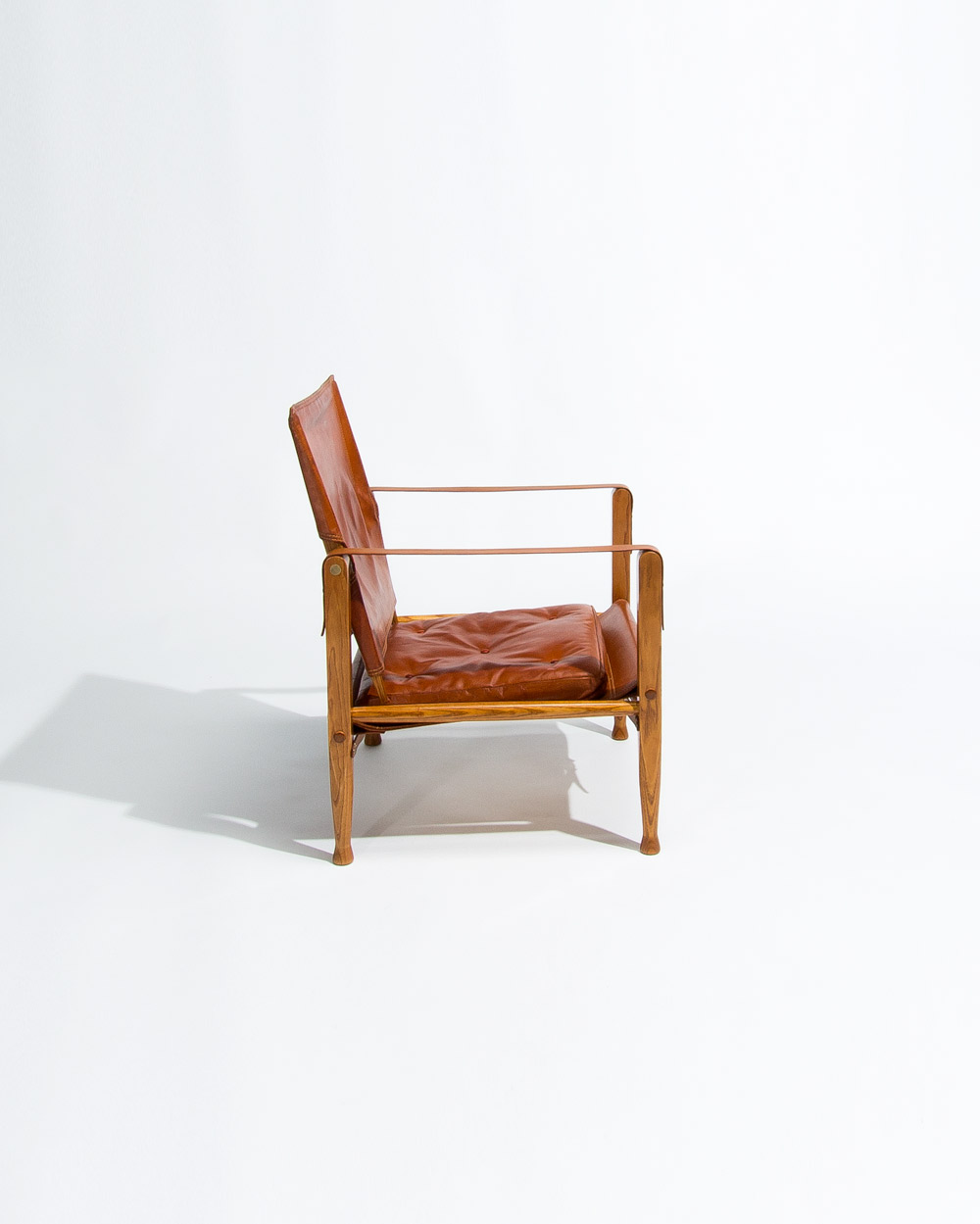 Side view of Kaare Klint Safari chair by Rud Rasmussen showing oak frame and leather seat