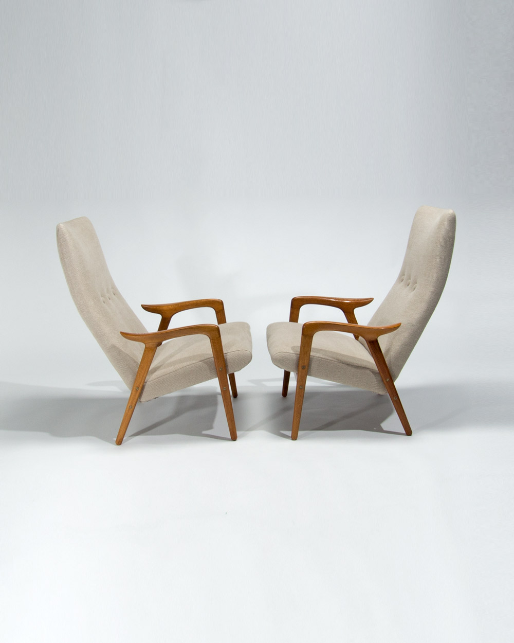 Side view of Yngve Ekstrom Swedish lounge chairs with sculptural oak armrests